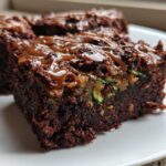 A close-up of a rich, dark chocolate Salted Caramel Swirl Zucchini Brownies square topped with gooey caramel drizzle.