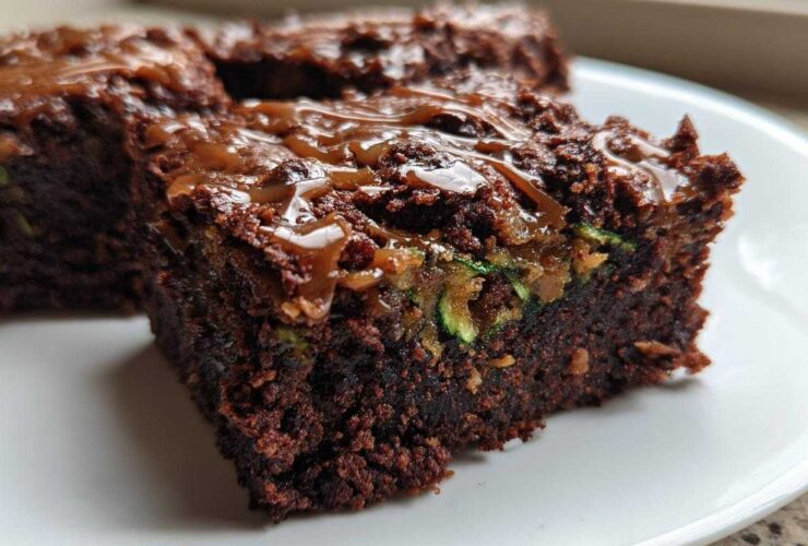 A close-up of a rich, dark chocolate Salted Caramel Swirl Zucchini Brownies square topped with gooey caramel drizzle.