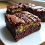 A rich, fudgy Salted Caramel Swirl Zucchini Brownies square showing a layer of caramel and visible green zucchini shreds.