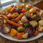 A white platter piled high with roasted chicken pieces, carrots, potatoes, red onion, and Brussels sprouts from Sheet Pan Harvest Chicken and Veggies.
