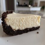 A perfect slice of creamy No bake cheesecake featuring a thick, dark chocolate cookie crust.