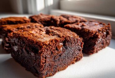 Close-up of several squares of Ultimate Fudgy Zucchini Brownies showing a rich, dark interior and melted chocolate chips.