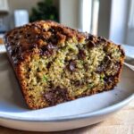 A close-up view of a freshly baked Ultimate Moist Chocolate Chip Zucchini Bread loaf showing its moist crumb and melted chocolate chips.