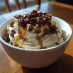 A bowl of creamy whipped goat cheese topped with candied pecans and a drizzle of honey.