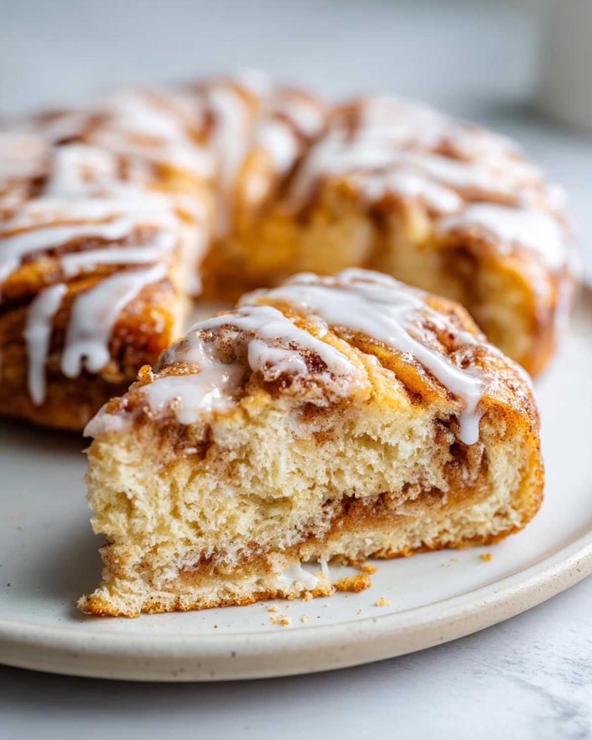Close-up of a soft slice taken from a Wisconsin apple kringle, showing cinnamon filling and white glaze.