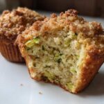 Close-up of a Zucchini Streusel Muffin cut in half showing moist crumb and green zucchini shreds, topped with streusel.