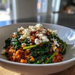 A close-up of a white bowl filled with the 1 Pot Feta and Lentil Spinach Dinner, topped with crumbled feta.
