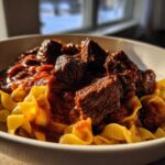 A close-up of rich, slow-cooked beef ragu served over wide egg noodles, capturing The Authentic Flavor Experience.