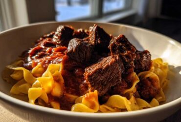 A close-up of rich, slow-cooked beef ragu served over wide egg noodles, capturing The Authentic Flavor Experience.