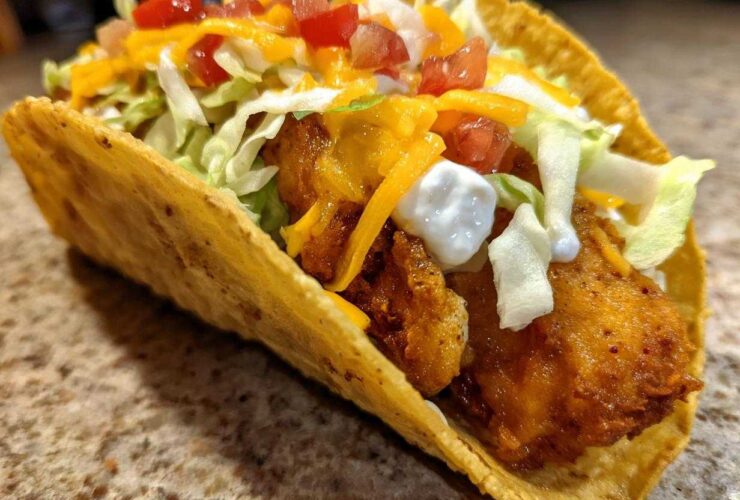 A close-up view of a crispy taco shell filled with golden Air Fried Fish Walking Tacos toppings.