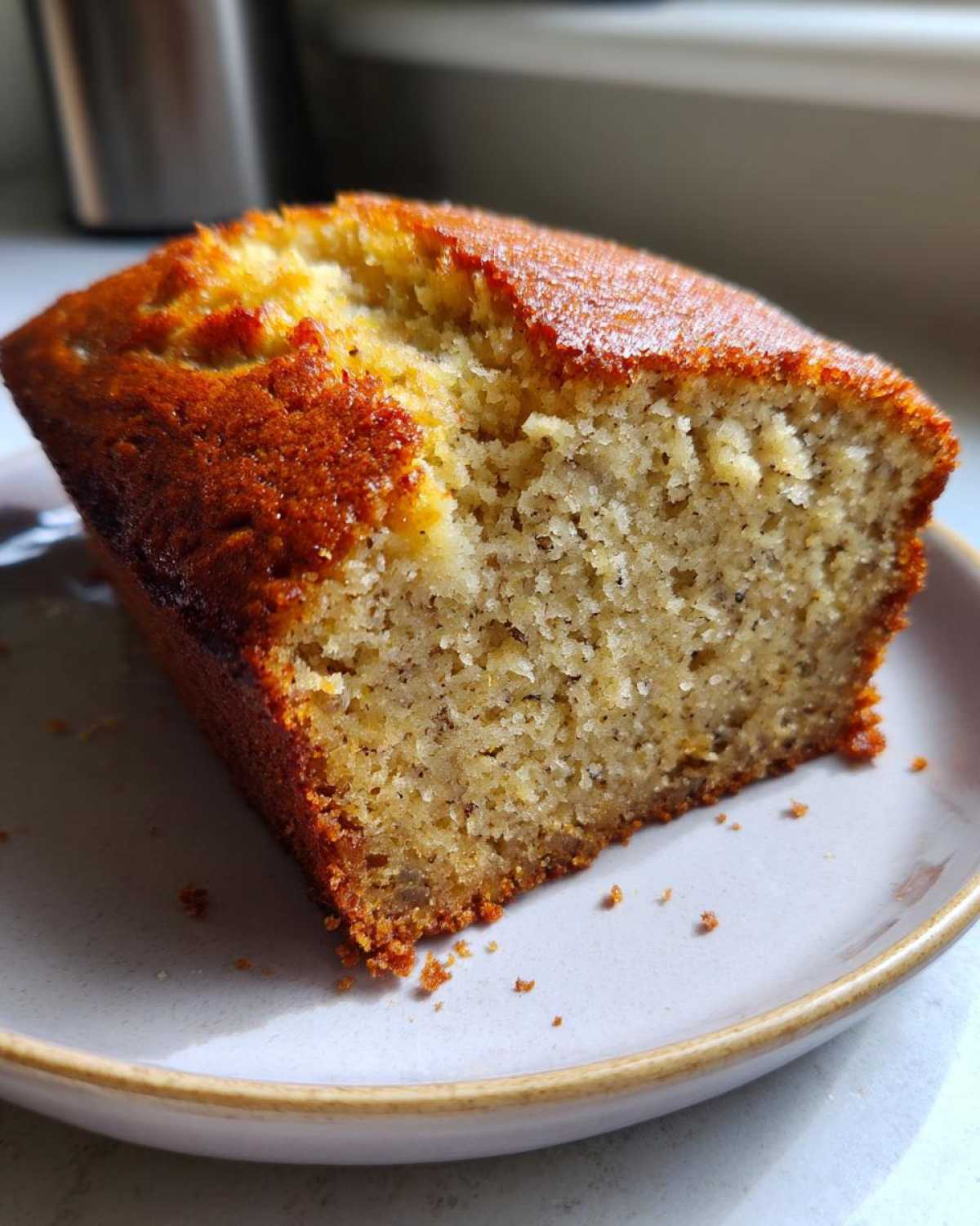 Close-up of a moist slice of Banana Bread Snack Cake showing its soft, textured crumb and golden-brown crust.