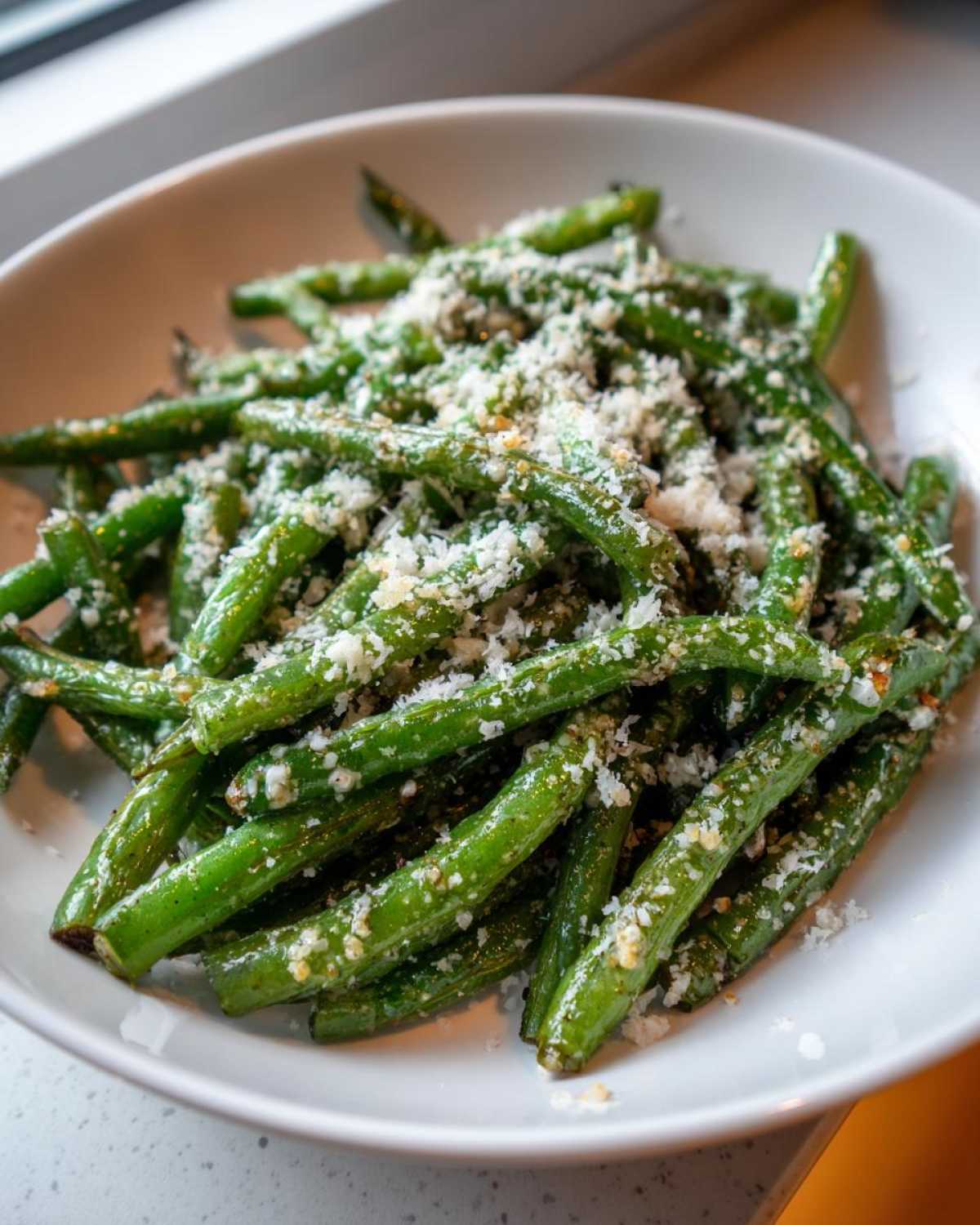 Close-up of vibrant green beans tossed with grated Parmesan cheese, ready to serve as The Best Garlic Parmesan Green Beans.