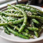 A close-up of bright green beans tossed in garlic and topped generously with grated Parmesan cheese: The Best Garlic Parmesan Green Beans.