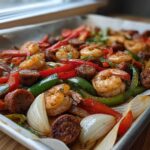 Close-up of Cajun Shrimp and Sausage Sheet Pan with roasted peppers and onions on parchment paper.