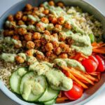 Overhead view of a vibrant Chickpea Grain Bowl with avocado lemon tahini dressing drizzled over roasted chickpeas and quinoa.
