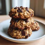 A stack of three homemade Chocolate Chip Banana Oatmeal Cookie treats piled high on a light gray plate.