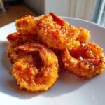 A close-up of several pieces of crispy, glazed Classic Bang Bang Shrimp For One piled on a white plate.