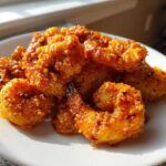 A close-up of crispy, saucy Classic Bang Bang Shrimp For One piled on a white plate.