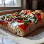 Close-up of two slices of Classic Homemade Margherita Pizza showing thick crust, melted mozzarella, red sauce, and fresh basil.