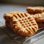 Close-up of a freshly baked Peanut Butter Cookie with classic crisscross fork marks resting on a wire cooling rack.