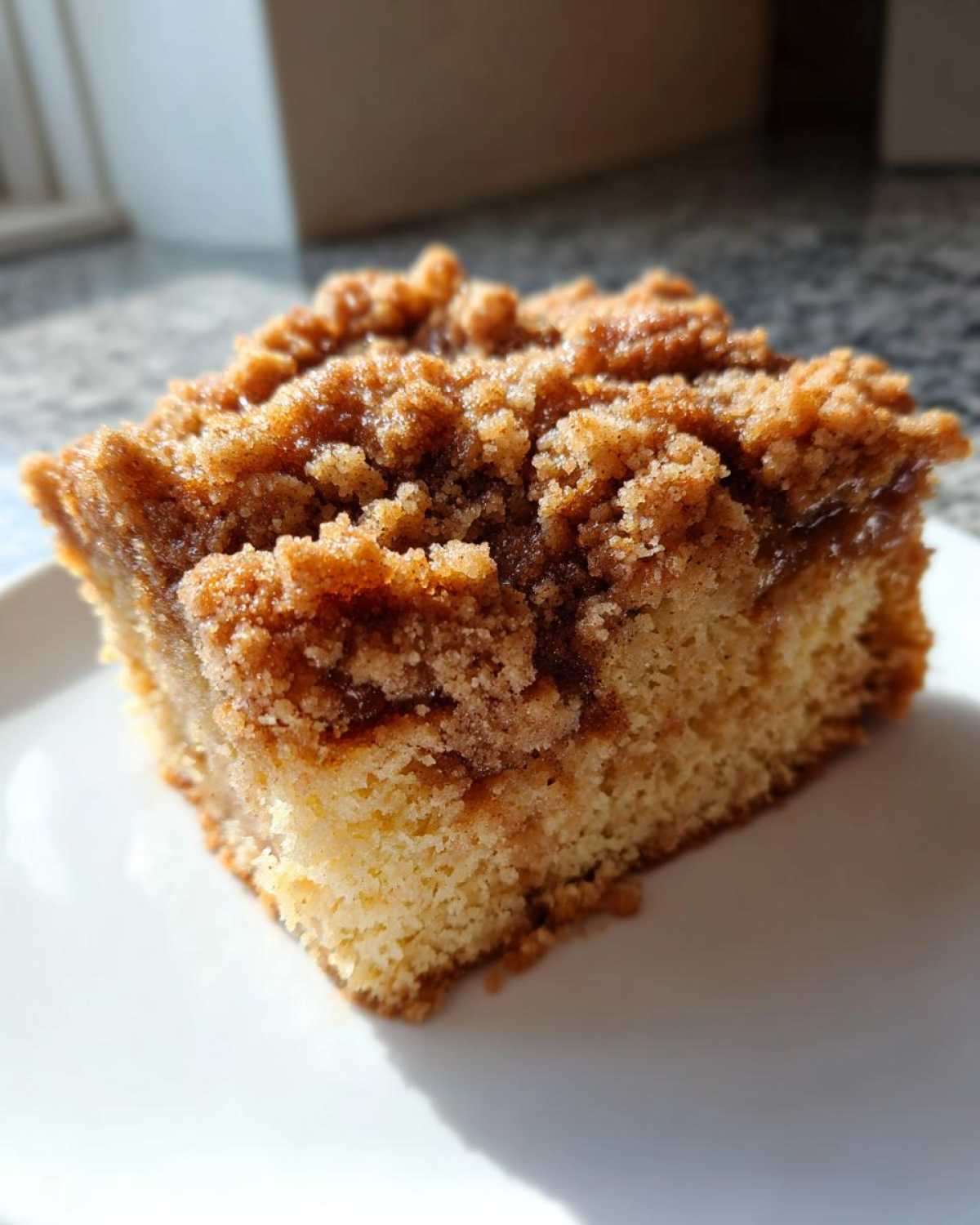 A close-up of a square slice of coffee cake featuring a thick, golden Cinnamon Coffee Cake Crumb Topping.