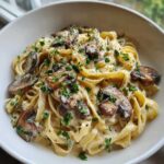 A close-up of rich Creamy Garlic Mushroom Pasta featuring fettuccine coated in a white sauce, topped with sautéed mushrooms and fresh parsley.