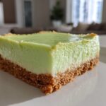 Close-up of a perfectly cut square of Creamy Key Lime Pie Bars showing a thick graham cracker crust and bright green filling.
