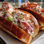 Close-up of two freshly made Lobster Roll sandwiches overflowing with creamy lobster salad and celery.