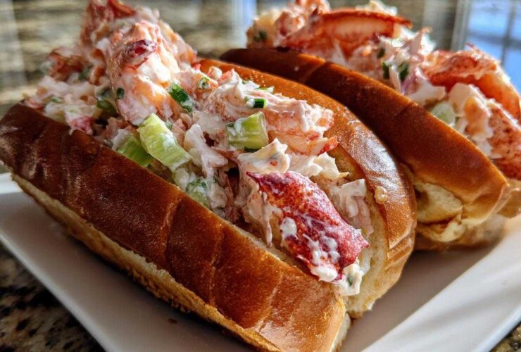 Close-up of two freshly made Lobster Roll sandwiches overflowing with creamy lobster salad and celery.