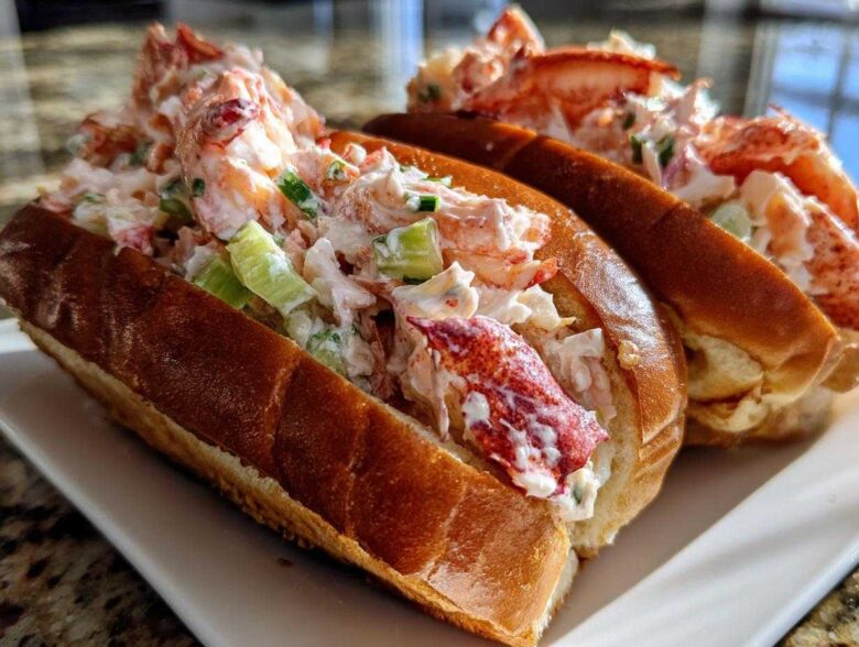 Close-up of two freshly made Lobster Roll sandwiches overflowing with creamy lobster salad and celery.