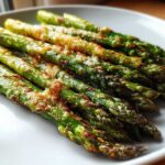 A close-up of perfectly cooked Crispy Roasted Asparagus A Side Dish for Christmas, topped with browned cheese.