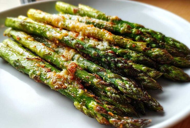 A close-up of perfectly cooked Crispy Roasted Asparagus A Side Dish for Christmas, topped with browned cheese.
