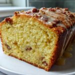 Close-up of a moist slice of Delicious Butter Pecan Pound Cake topped with a pecan glaze drizzle.