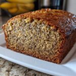 Close-up of a slice of moist Favorite Banana Bread showing the dark, speckled interior and caramelized top crust.