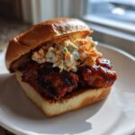 A delicious Gochujang Chicken Burger featuring glazed chicken and creamy slaw on a brioche bun, served on a white plate.