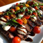 Slices of Grilled Flank Steak Caprese topped with mozzarella balls, cherry tomatoes, basil, and balsamic glaze.