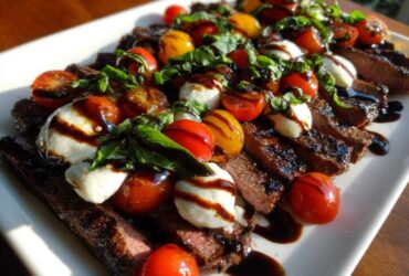 Slices of Grilled Flank Steak Caprese topped with mozzarella balls, cherry tomatoes, basil, and balsamic glaze.