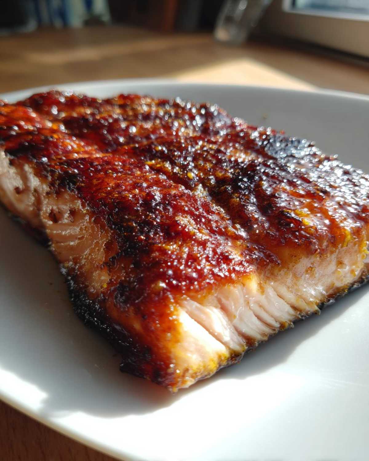 A close-up of a perfectly cooked fillet of Grilled Honey Mustard Salmon with a dark, caramelized glaze on a white plate.