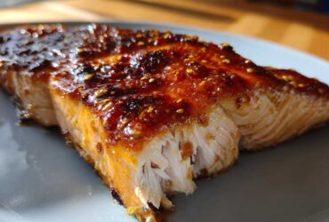 Close-up of a flaky Grilled Honey Mustard Salmon fillet with a shiny, caramelized glaze and visible mustard seeds.