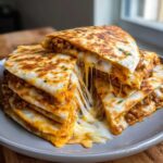 A stack of cheesy Ground Beef Quesadillas cut into wedges, showing a dramatic cheese pull.
