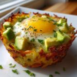 A single, crispy Hash Brown Avocado Egg Cup featuring a baked egg topped with diced avocado and herbs.