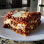 A perfect, thick slice of Homemade Classic Beef Lasagna showing layers of meat sauce, ricotta, and melted cheese.