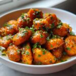 Close-up of bright orange Honey Garlic Butter Roasted Carrots coated in a sticky glaze and sprinkled with fresh parsley.