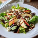 A vibrant Honeycrisp Apple Feta Salad featuring crisp lettuce, sliced red apples, crumbled feta, pecans, and a balsamic glaze drizzle.