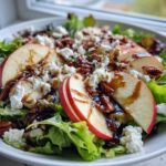 A vibrant Honeycrisp Apple Feta Salad featuring crisp lettuce, sliced red apples, crumbled feta cheese, pecans, and a balsamic glaze.