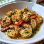 Close-up of succulent Lemon Garlic Shrimp coated in butter sauce and fresh parsley in a white bowl.