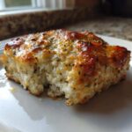 A close-up of a baked portion of Mayo Parmesan Cod showing the flaky white fish and browned, herbed cheese topping.