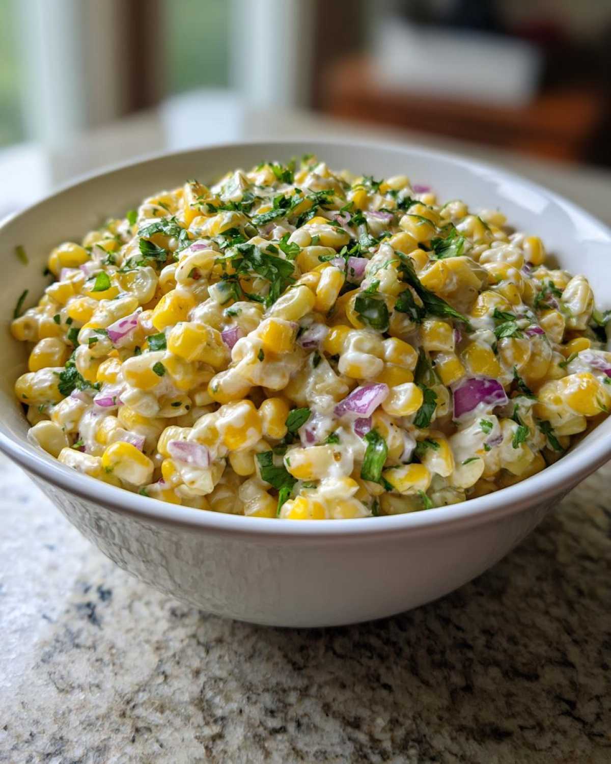 A close-up of a white bowl filled with creamy Mexican Street Corn Pasta Salad, topped with fresh cilantro.