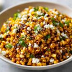Close-up of charred corn kernels mixed with cotija cheese and cilantro, ready to serve as Mexican Street Corn Salad Esquites.