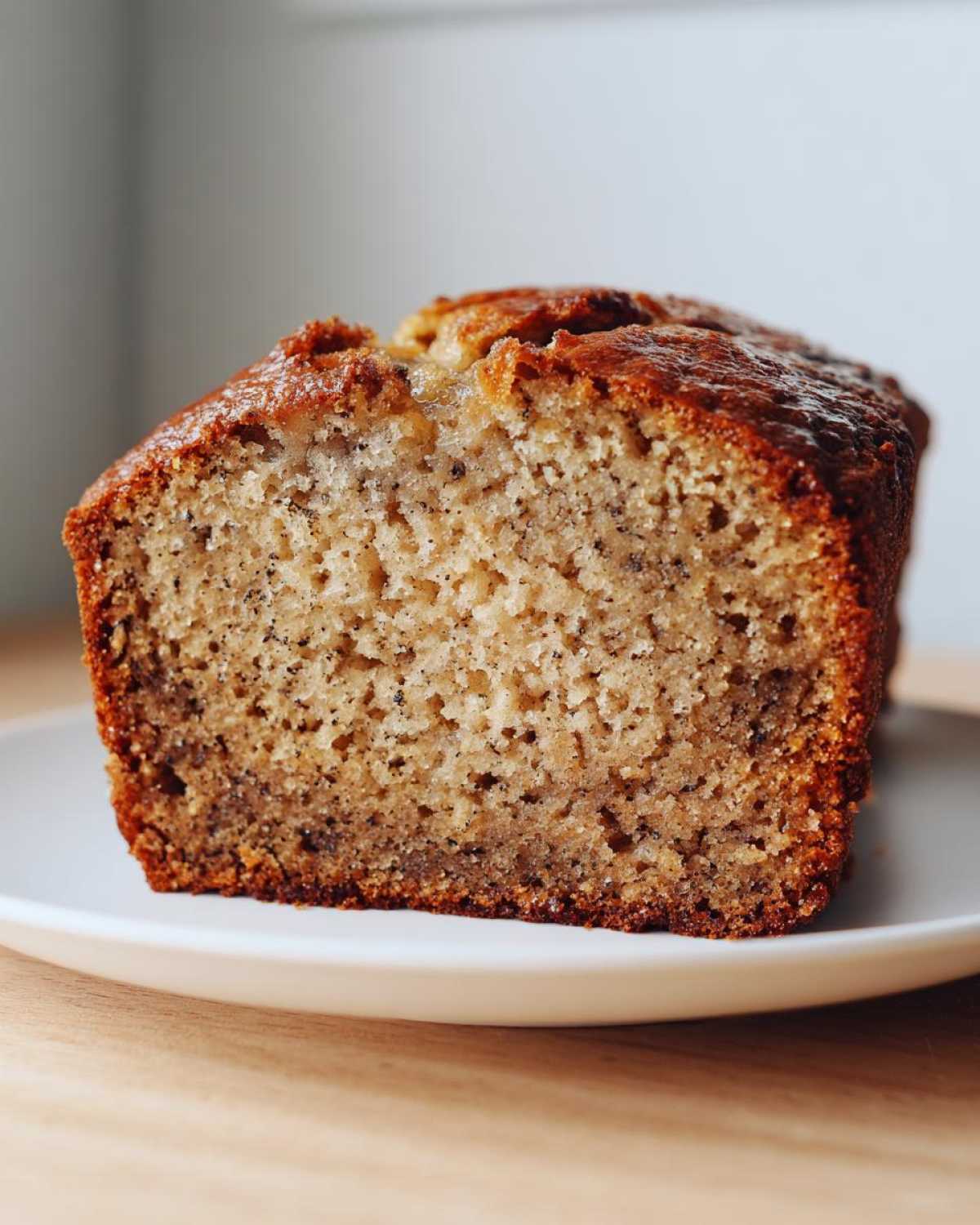 Close-up of a moist slice of Banana Bread showing the speckled interior and golden-brown crust.